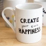 Close up image of a coffee mug that reads create your own happiness.