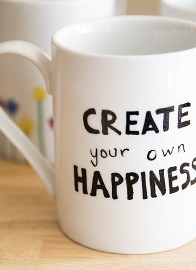Close up image of a coffee mug that reads create your own happiness.