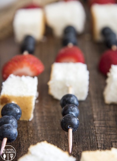 Red, white, and blue fruit kebabs above image on a wood background.