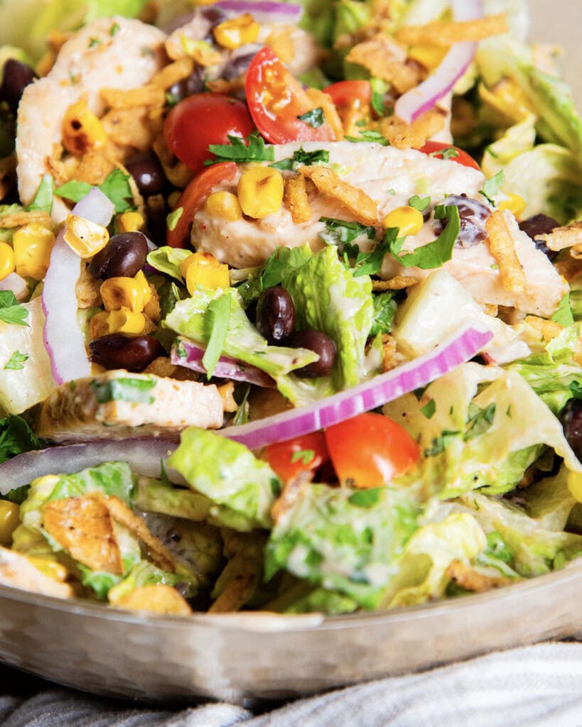 A tossed bbq ranch chicken salad loaded with chicken, tomatoes, and red onion.