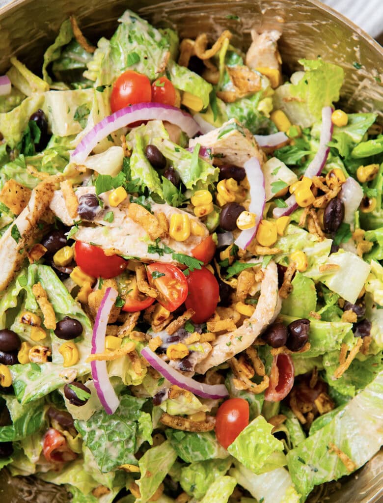 A tossed bbq ranch chicken salad loaded with chicken, tomatoes, and red onion.