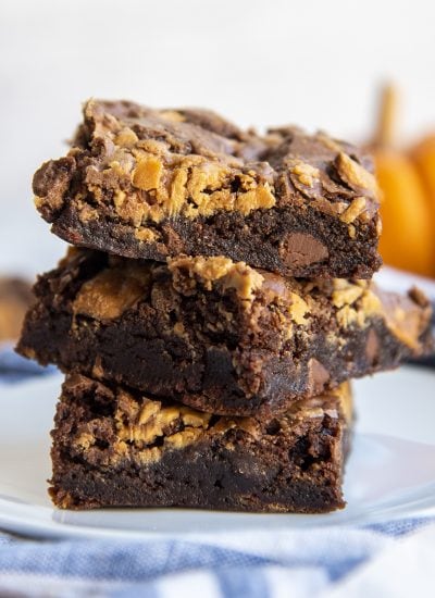 A stack of three peanut butter butterfinger brownies on a plate.