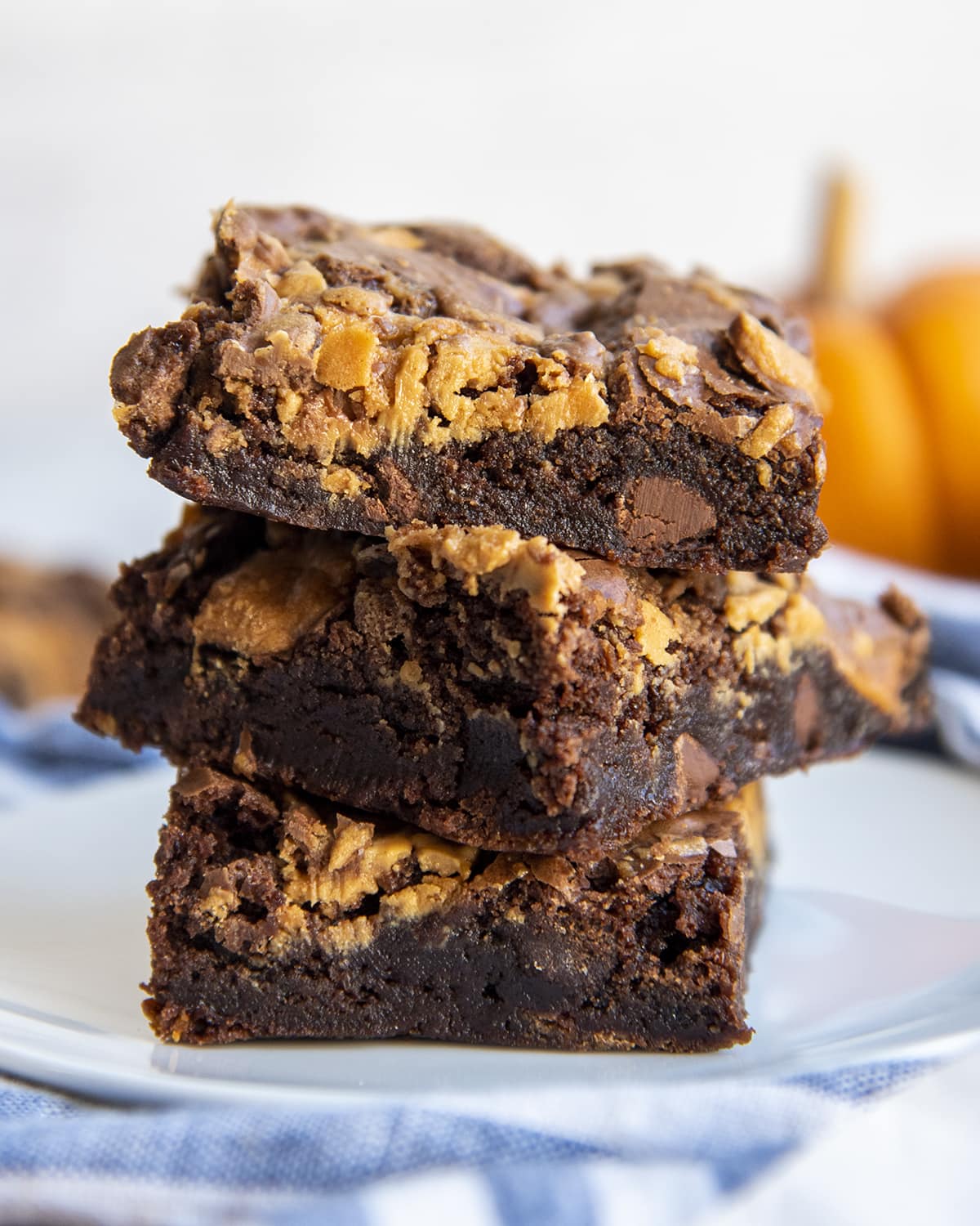 A stack of three peanut butter butterfinger brownies on a plate.