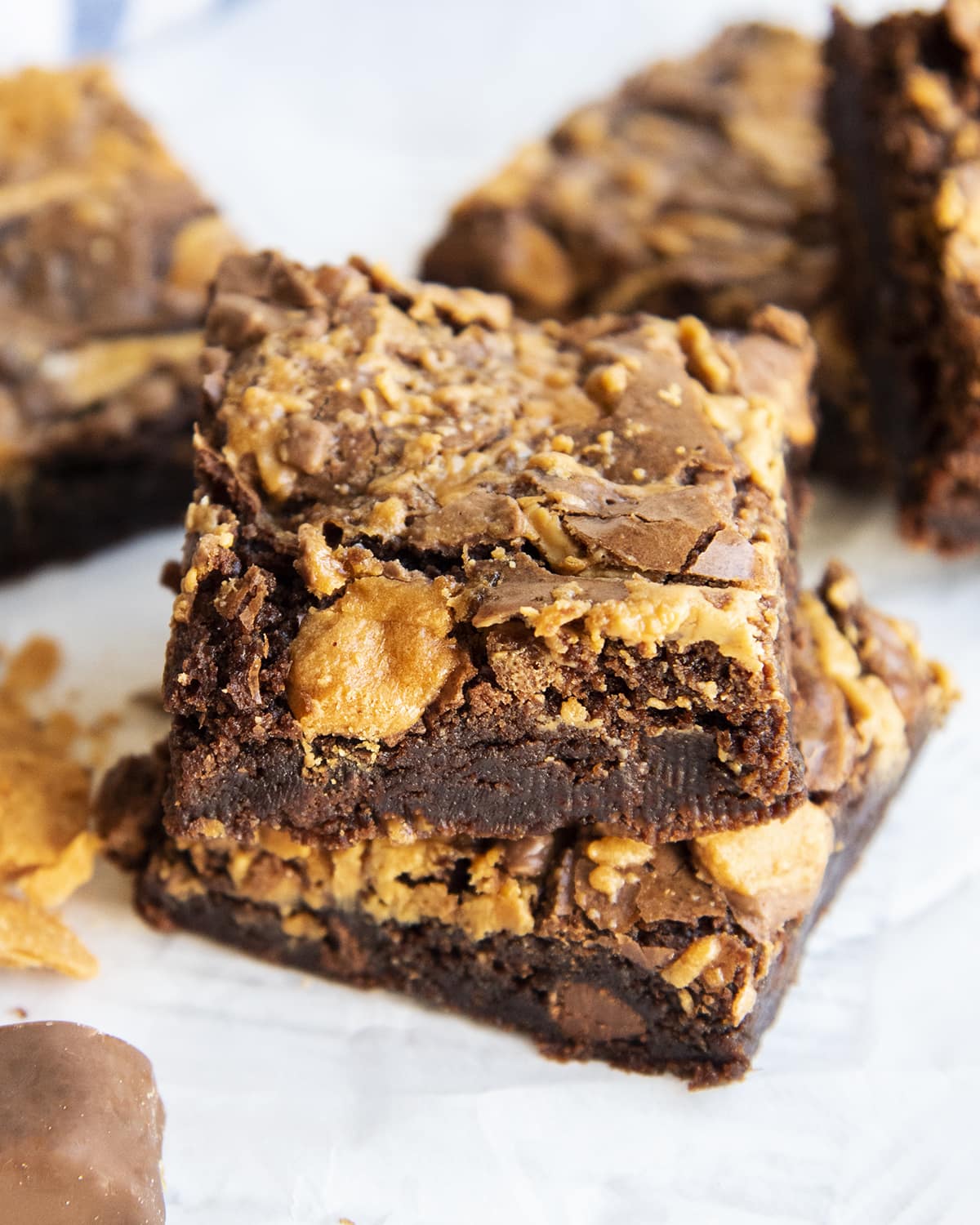 Two butterfinger brownies topped with peanut butter swirls and Butterfinger pieces.