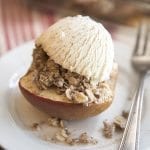 Above image of baked apples with a scoop of ice cream on top on a white plate.