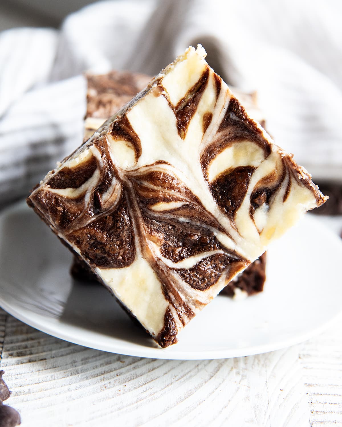A cheesecake swirled brownie with cheesecake and brownie marbled together, set on a plate.