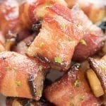 Bacon wrapped pineapple bites in a bowl topped with fresh herbs.