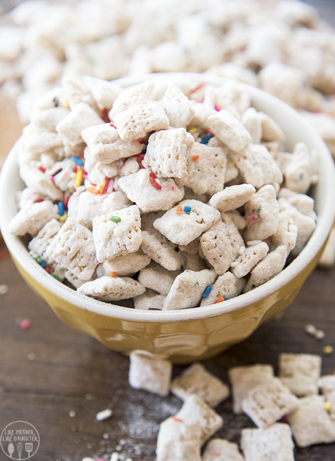 Cake batter muddy buddies are displayed in a bowl with rainbow sprinkles.