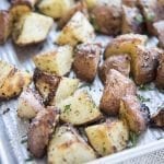 A pan of roasted red potatoes topped with black pepper and fresh parsley.
