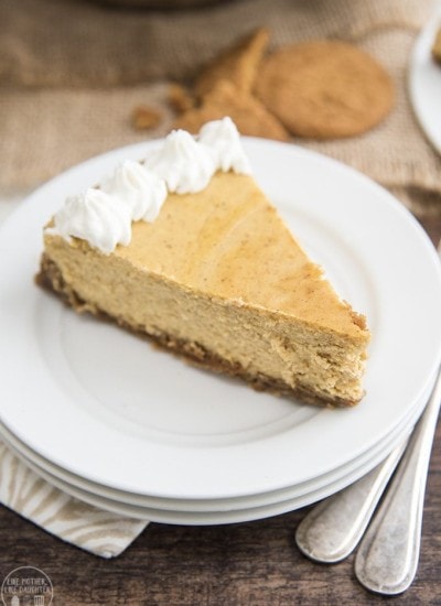 A slice of pumpkin cheesecake topped with whipped cream on the edge.