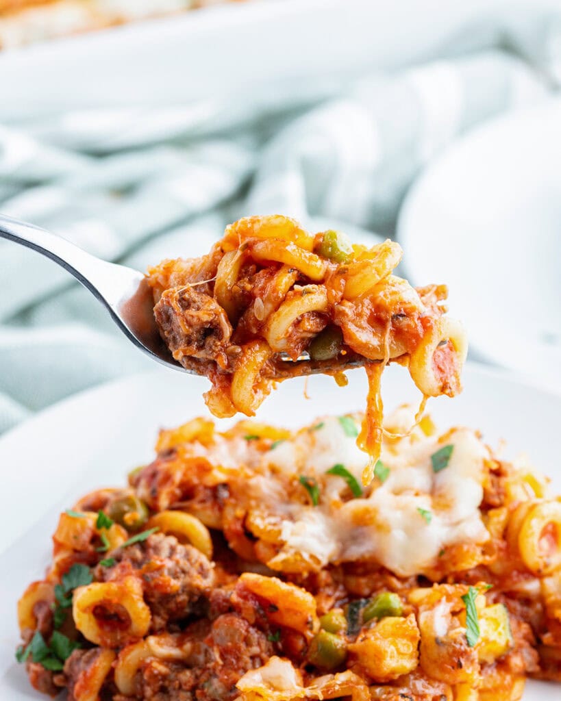 A spoonful of anelletti pasta above a plate of it.