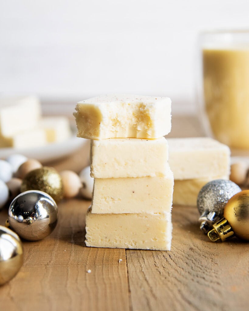 A stack of 4 eggnog fudge pieces, and the top piece has a bite out of it.