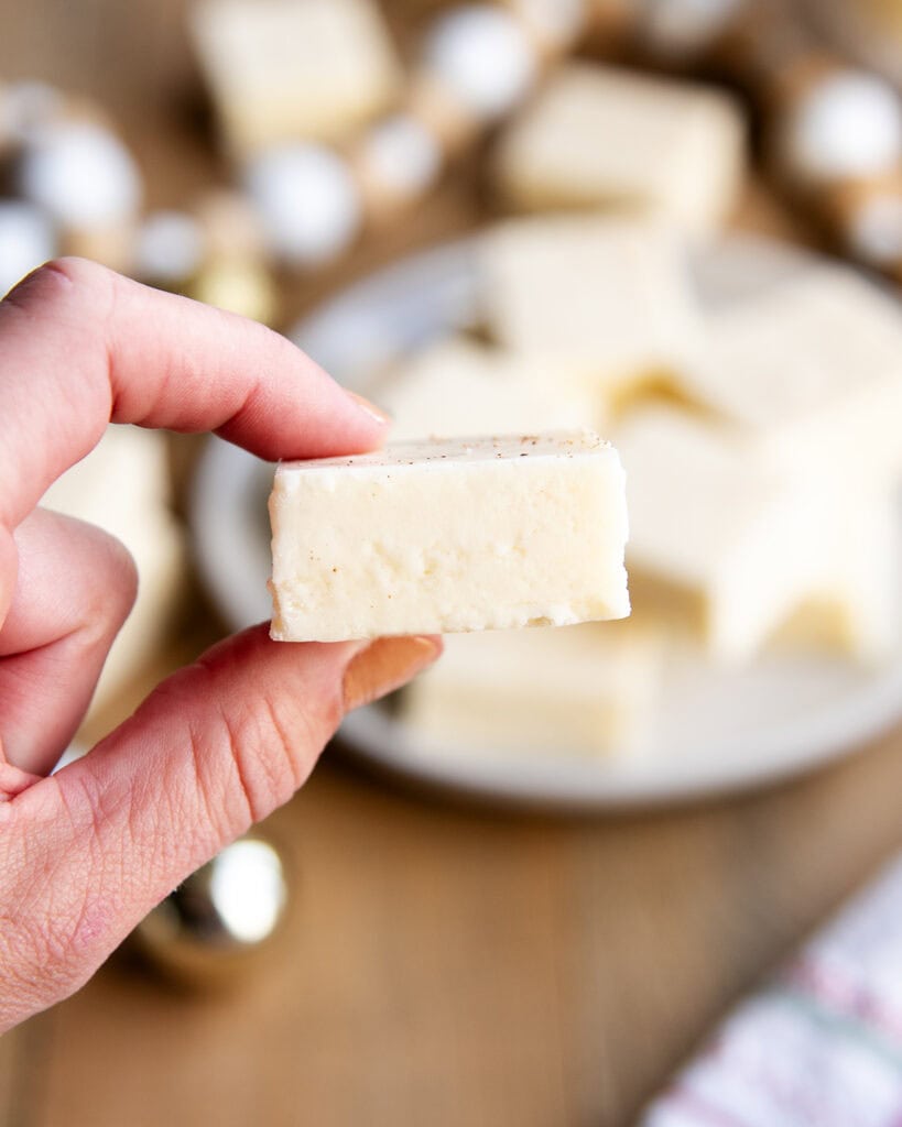 A hand holding a piece of eggnog fantasy fudge.