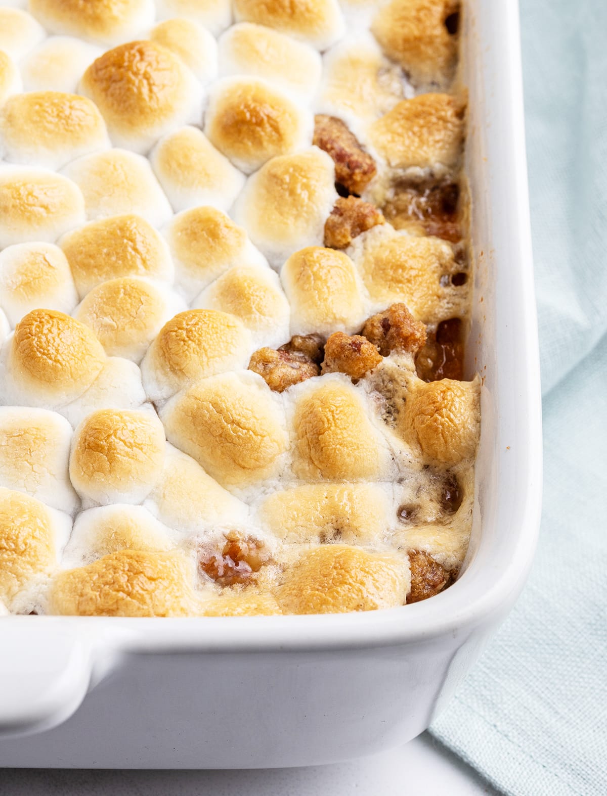 A close up of mini marshmallows toasted in a pan above some streusel topping.