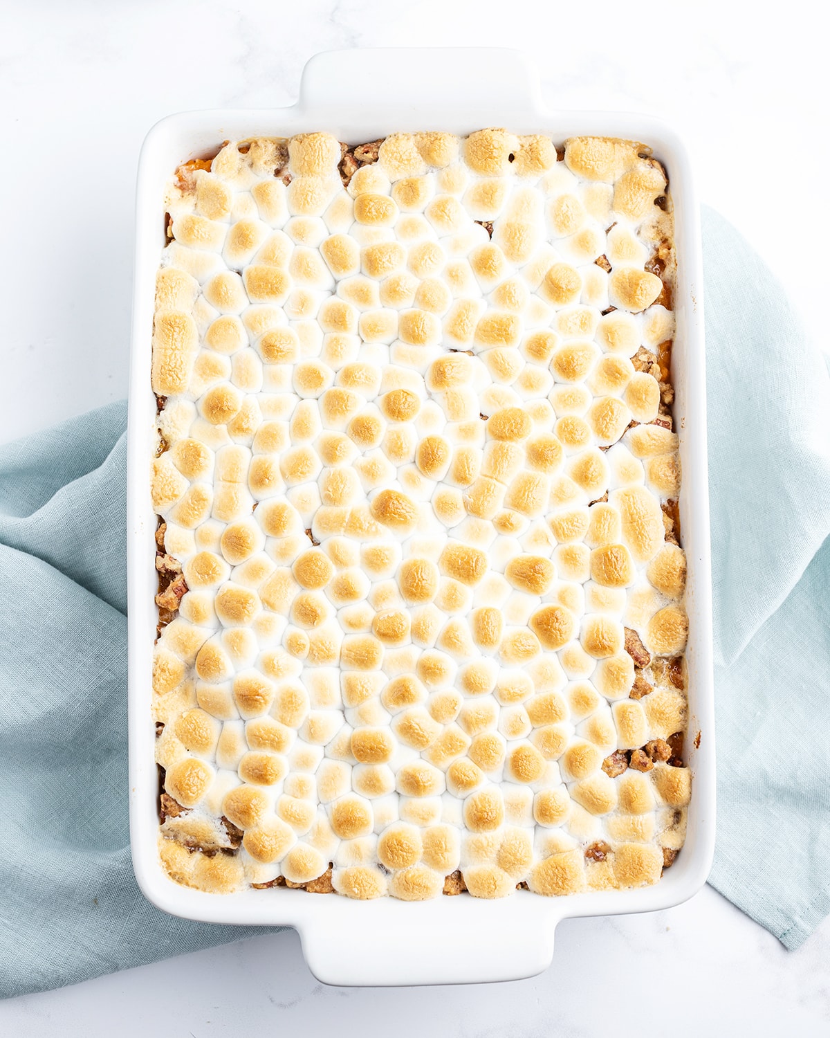 An overhead shot of a sweet potato casserole with toasted mini marshmallows on top.