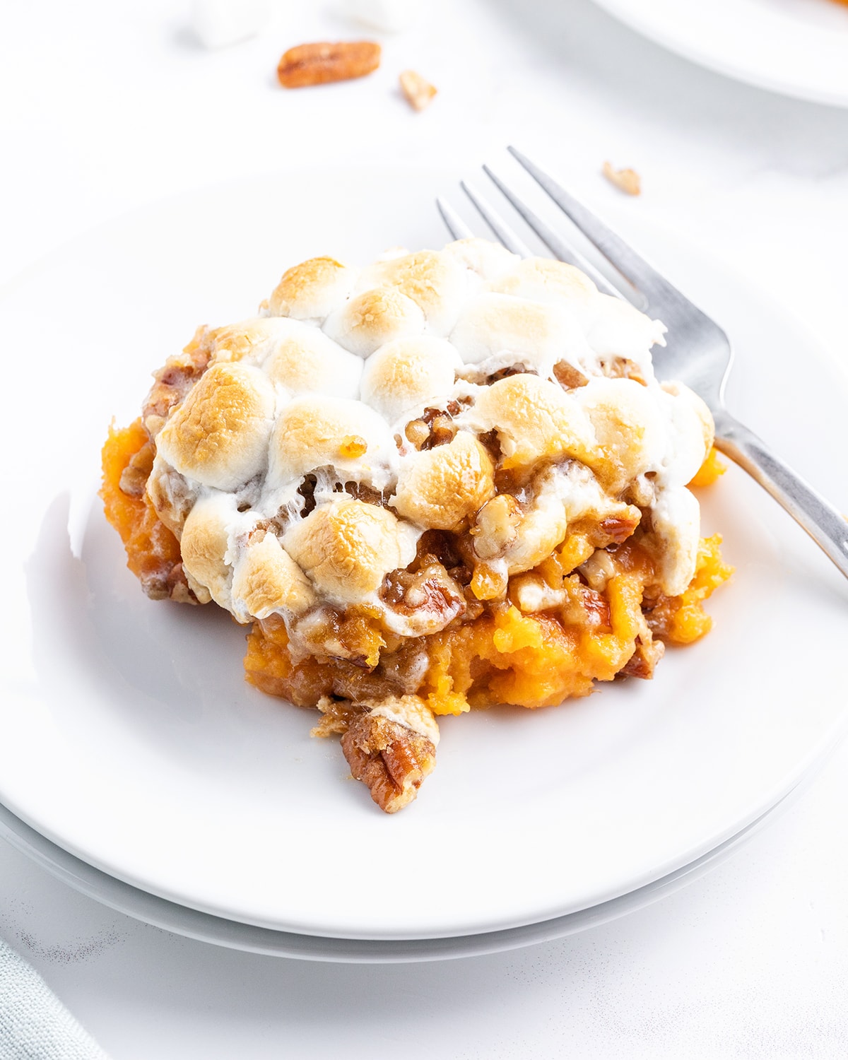 A plate of sweet potato casserole with candied pecans and toasted marshmallows on top.