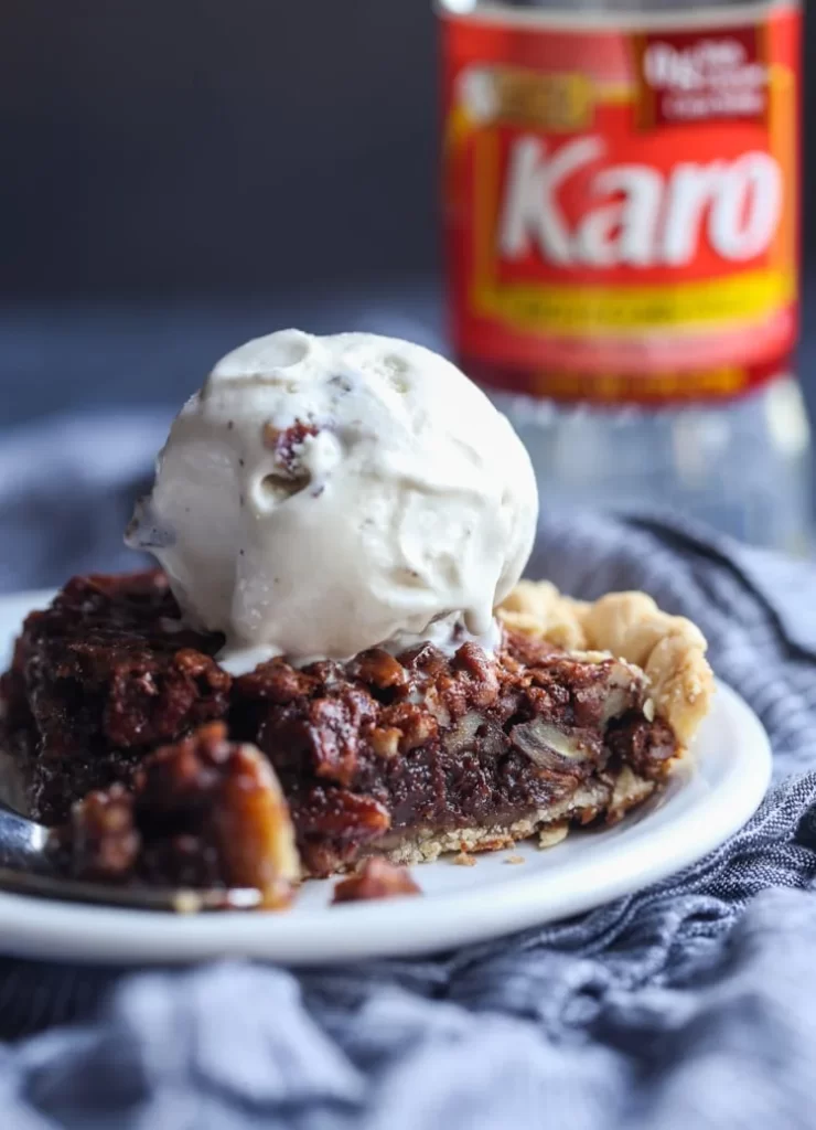 A slice of chocolate pecan pie topped with a scoop of vanilla ice cream.
