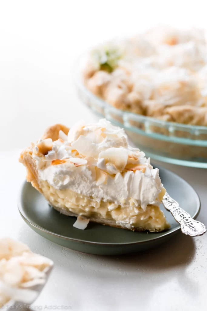 A slice of coconut cream pie topped with whipped cream and toasted coconut.