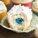 A cupcake with a bite out of the middle showing blue m&ms in the middle.