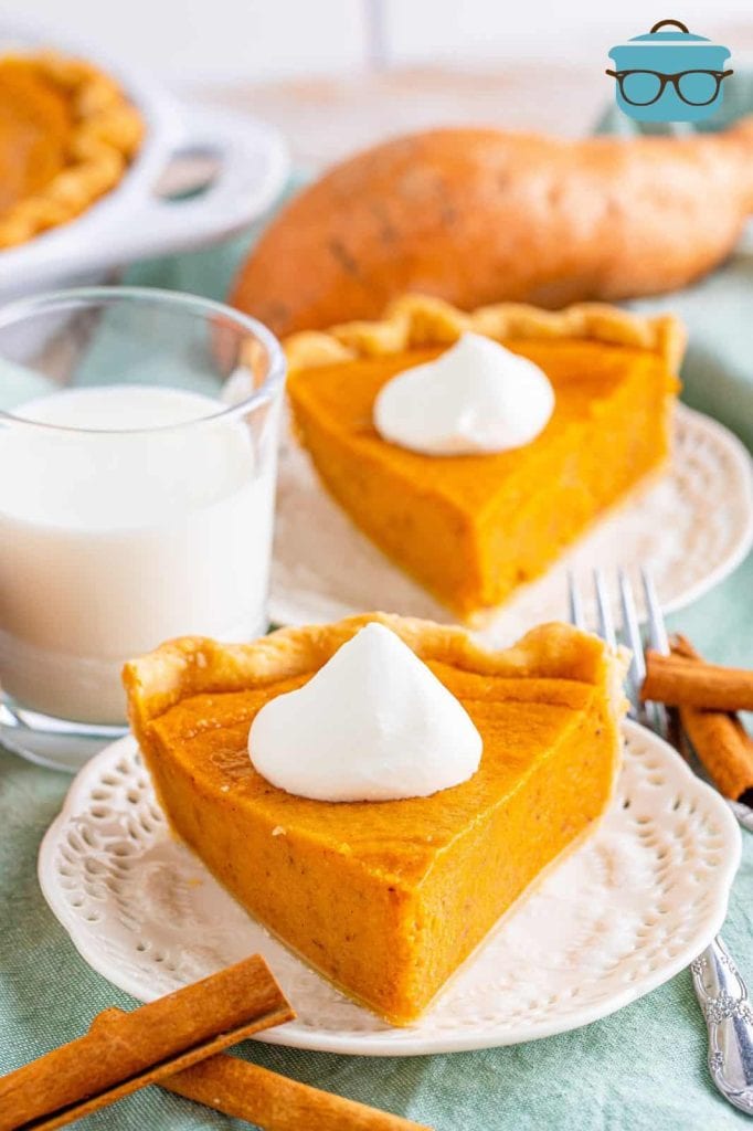 A slice of orange sweet potato pie topped with a dollup of whipped cream on a white plate.