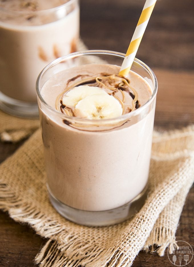 A glass of chocolate and peanut butter smoothie topped with bananas.