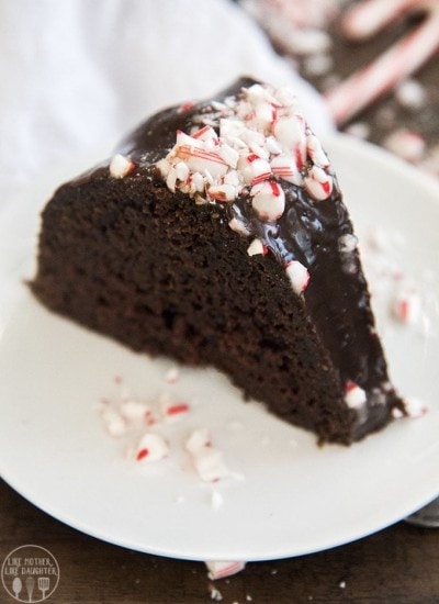 A slice of a chocolate bundt cake topped with chocolate ganache and chopped candy cane pieces.