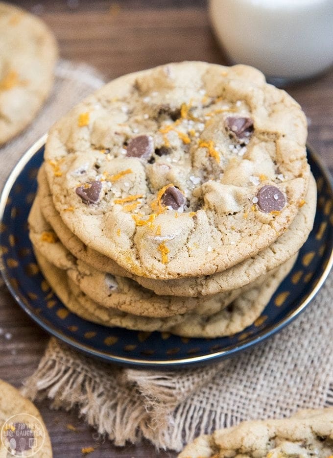 A stack of large chocolate chip and orange zest cookies on a blue plate.