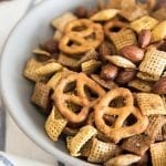 A bowl of homemade chex mix with almonds and pretzels.