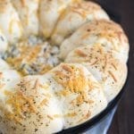 A skillet full of garlic bread rolls with spinach dip in the middle.