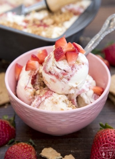 A pink bowl of strawberry cheesecake ice cream topped with diced strawberries.
