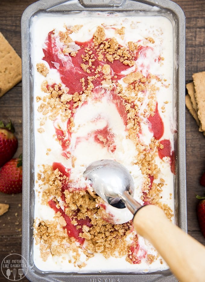 An overhead photo of a container of ice cream with a strawberry swirl on top. 