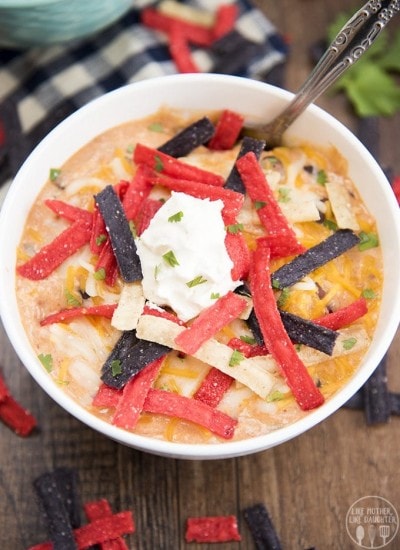 A bowl of creamy enchilada soup topped with tortilla strips and sour cream.