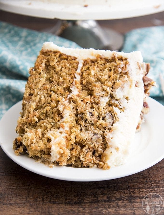 A slice of layered carrot cake is displayed on a plate with frosting.