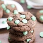 A stack of four chocolate cookies with green mint chips in them.