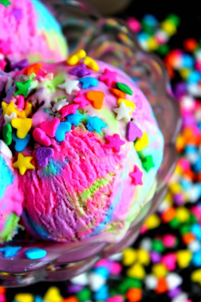 A bowl of pink unicorn ice cream topped with rainbow sprinkles. 
