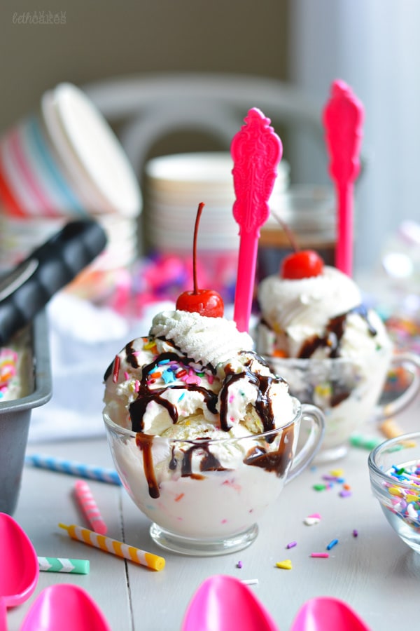 Bowls of no churn cake batter ice cream topped with chocolate syrup, whipped cream, and a cherry each. 