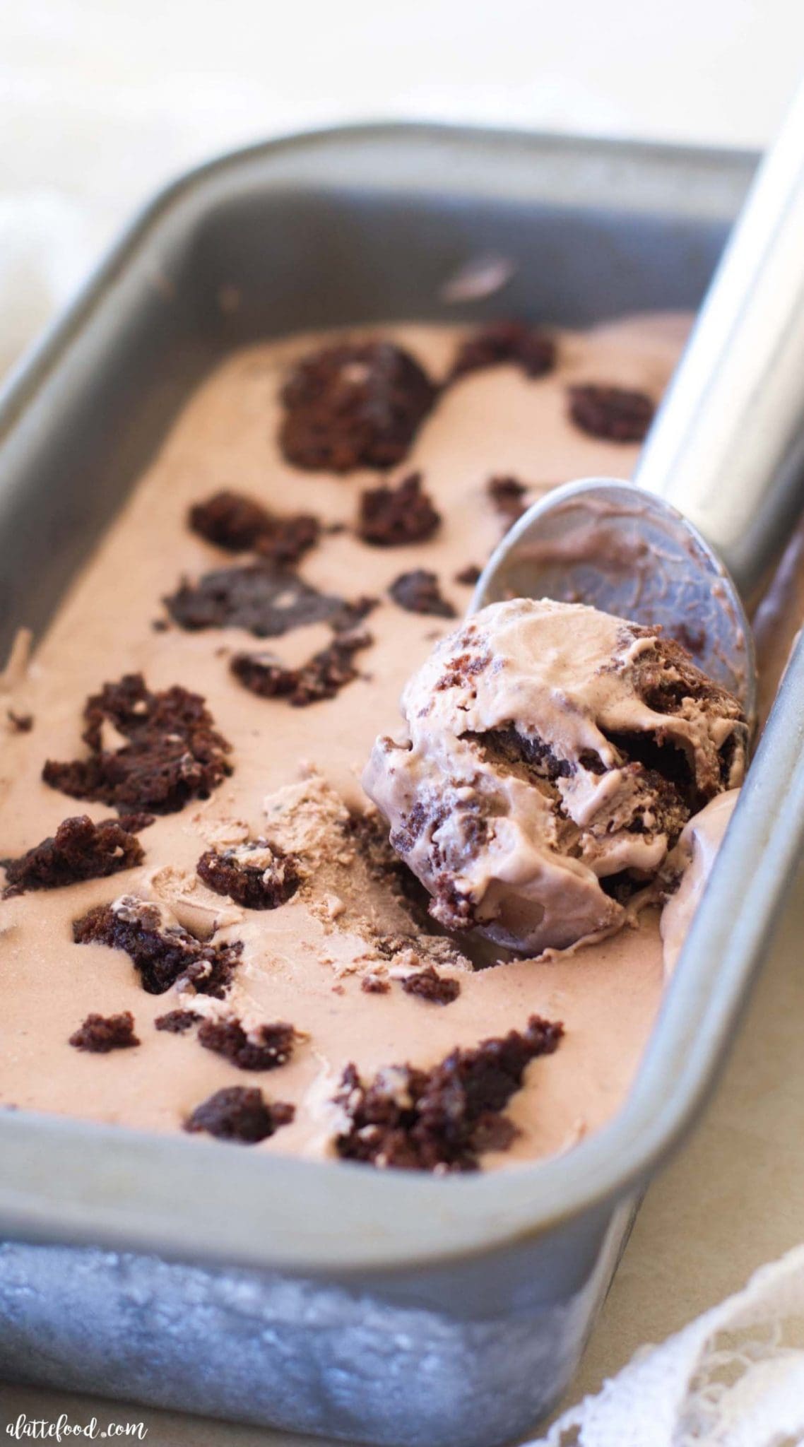A container of brownie ice cream with an ice cream scoop in it. 