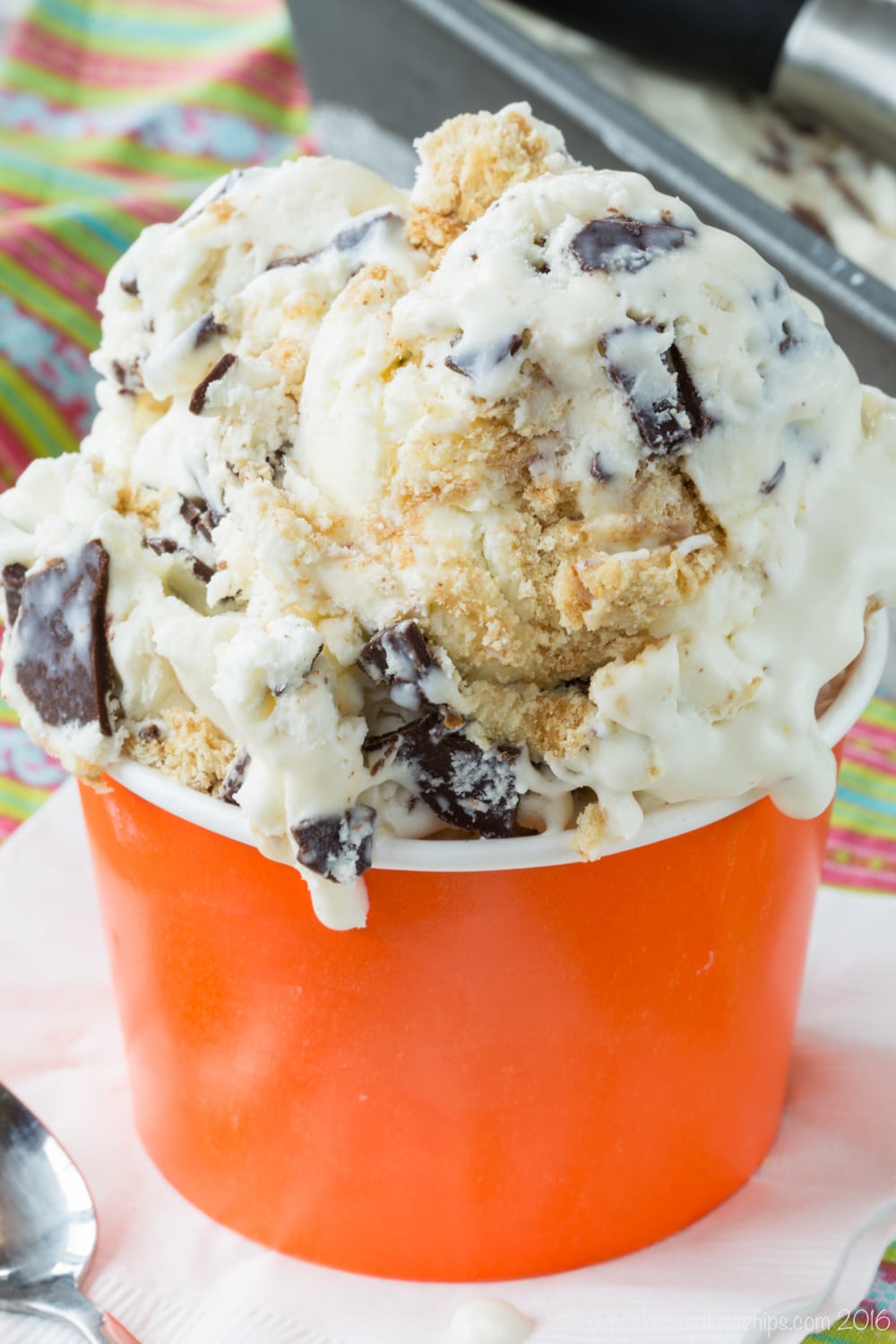 An orange paper cup full of graham cracker and chocolate chunk ice cream. 