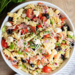 An above view of Italian pasta salad with pepperoni, mozzarella, tomatoes, olives, and pasta in a bowl.