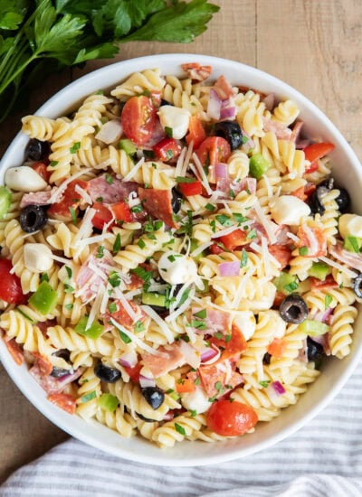 An above view of Italian pasta salad with pepperoni, mozzarella, tomatoes, olives, and pasta in a bowl.