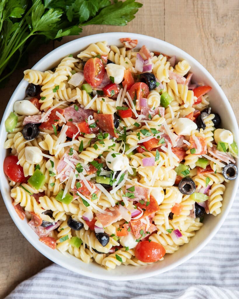 An above view of Italian pasta salad with pepperoni, mozzarella, tomatoes, olives, and pasta in a bowl.