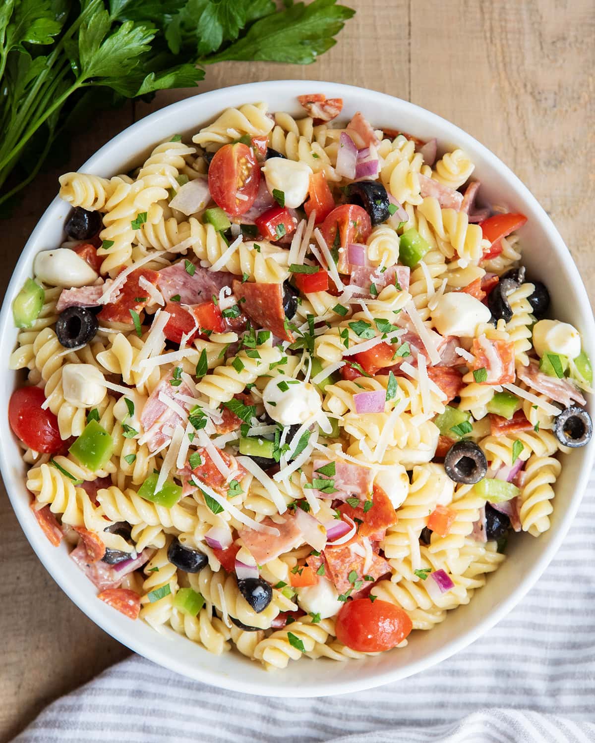 An above view of Italian pasta salad with pepperoni, mozzarella, tomatoes, olives, and pasta in a bowl.