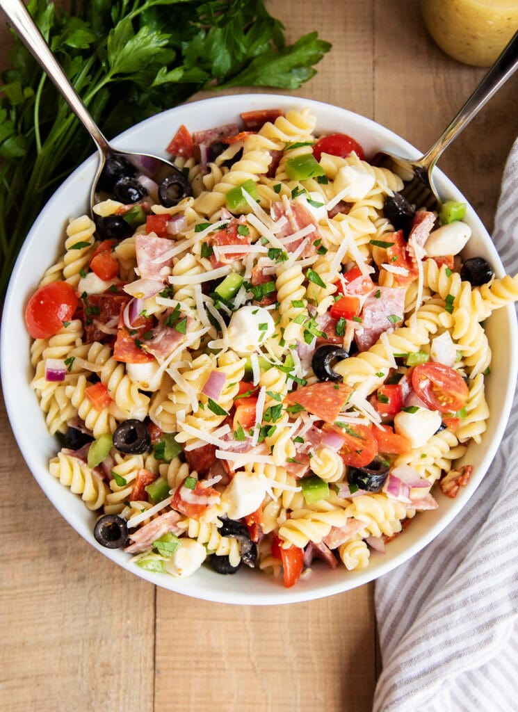 An above view of Italian pasta salad with pepperoni, mozzarella, tomatoes, olives, and pasta in a bowl.