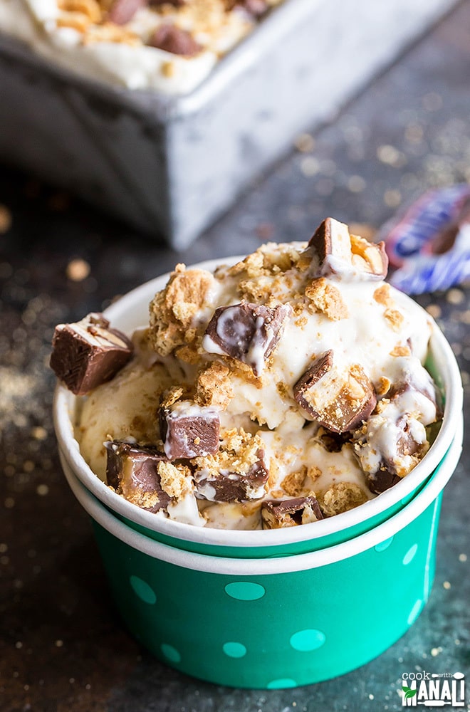 A paper bowl full of snickers cheesecake ice cream topped with chopped up snickers. 