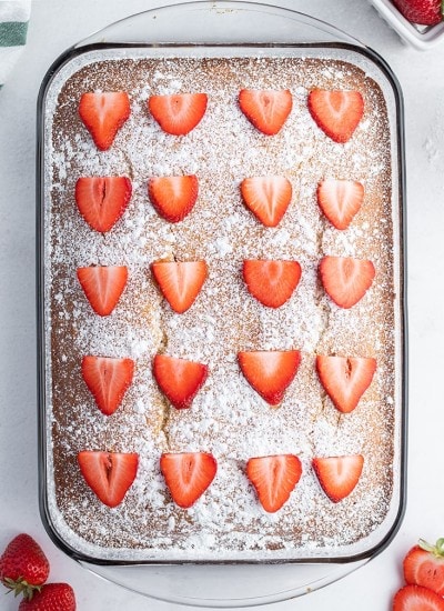 A strawberry yogurt cake topped with powdered sugar and sliced strawberries