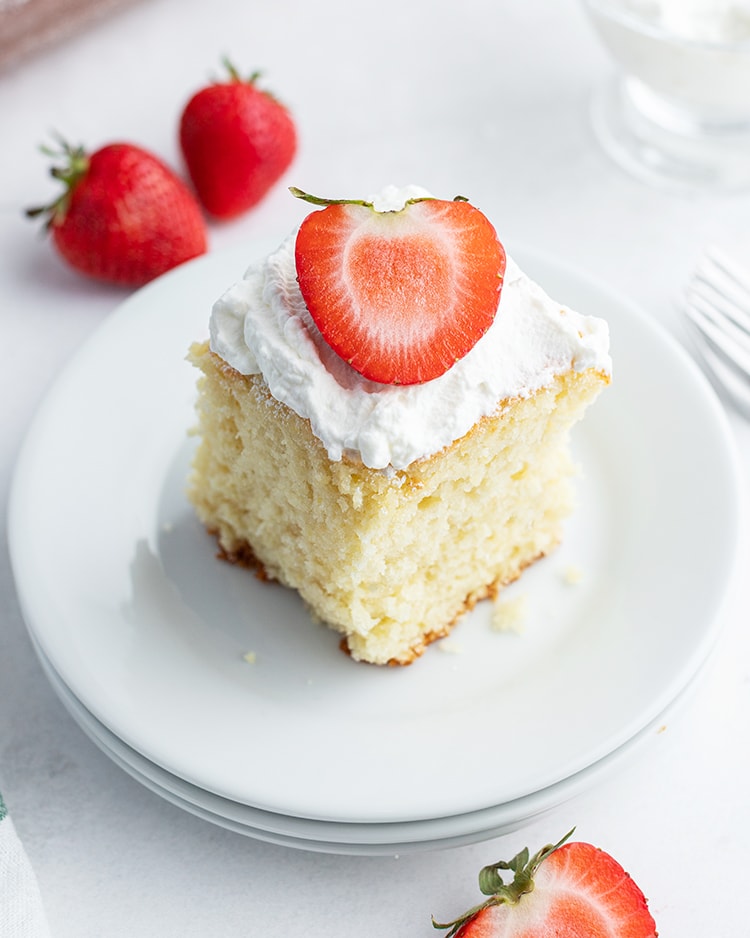 Strawberry yogurt cake topped with whipped cream and a strawberry.
