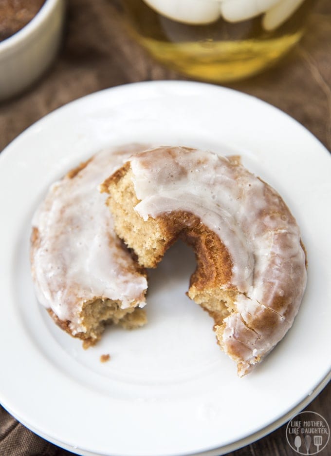 An apple cider donut on a plate broken into two halves.