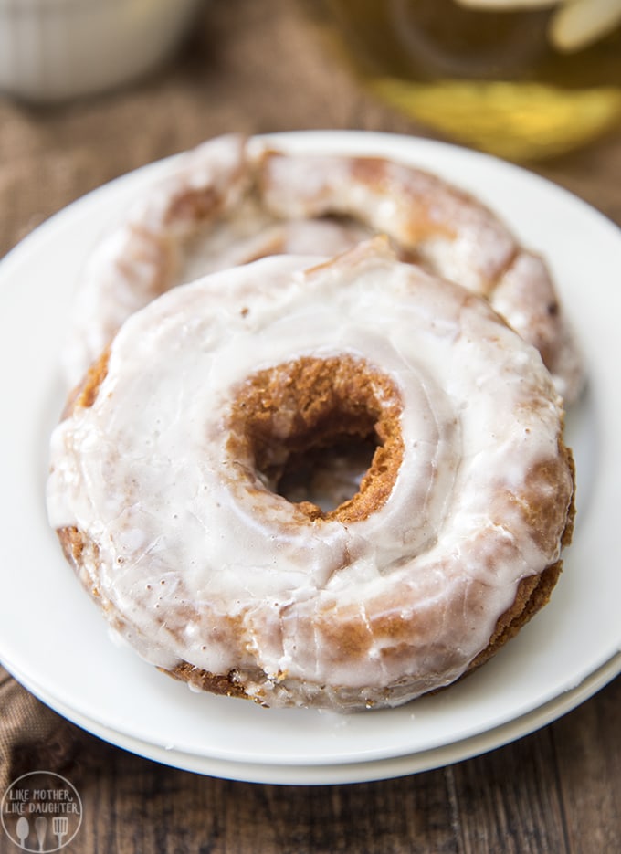 Two apple cider donuts topped with a glaze on a plate.