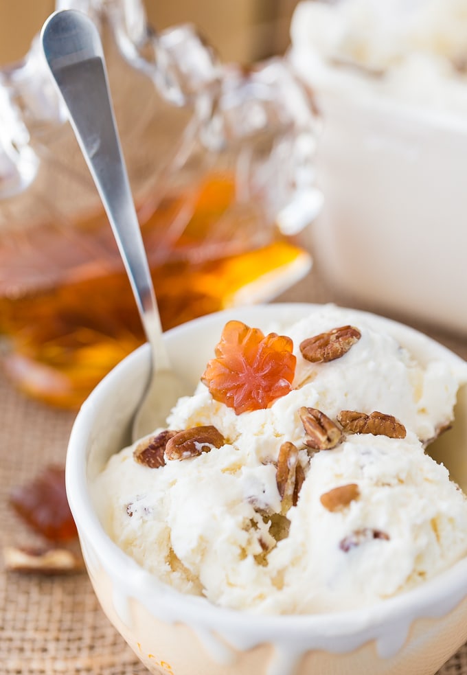 A bowl of maple pecan ice cream topped with chopped pecans and a maple candy. 
