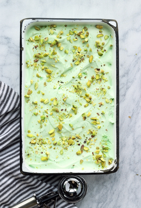 An overhead photo of a container of green pistachio ice cream. 